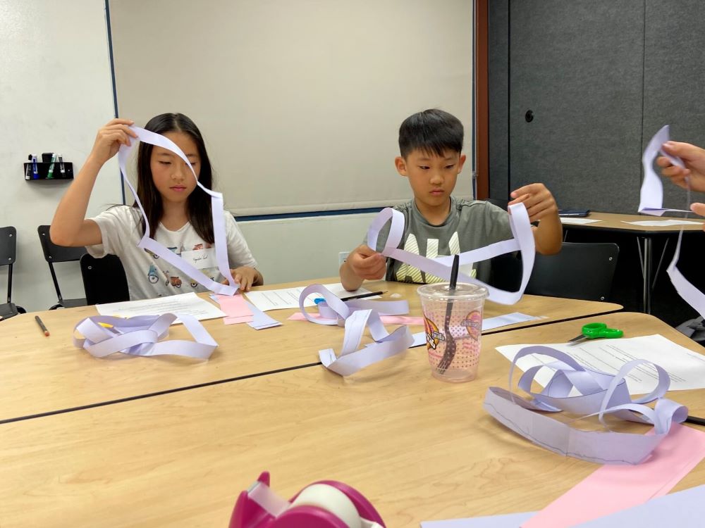Two Math Adventures students experiment with Möbius strips